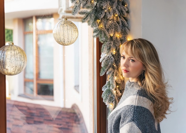 Portrait of a beautiful blonde woman wearing warm sweater adult attractive woman at home poses by