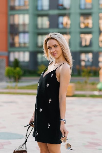 Portrait of a beautiful blonde young woman in a black dress with straps