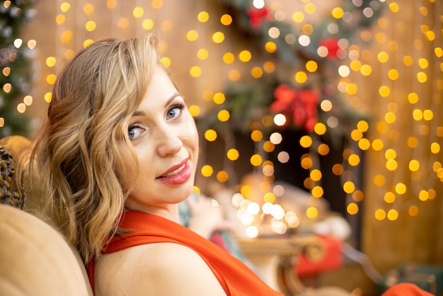 portrait of a beautiful blonde young woman sitting in a room decorated for the new year celebration. selective focus, artistic blur