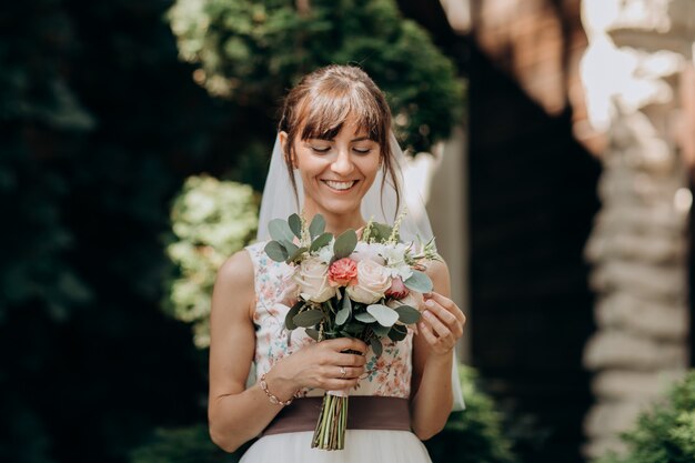 Portrait of a beautiful bride in veil with a bouquet of flowers in his hands