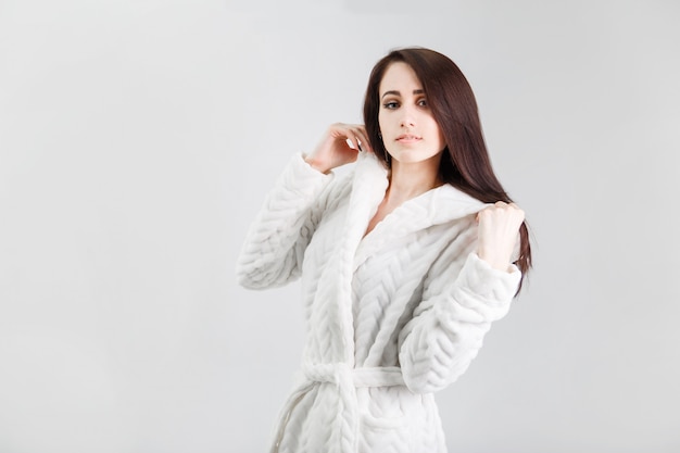 Portrait of Beautiful brunette woman on white background wearing white bathrobe