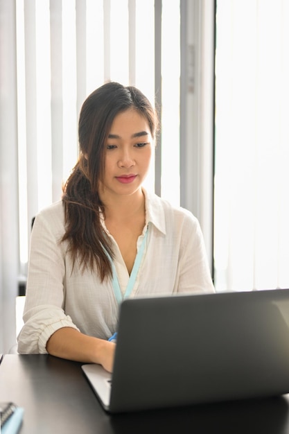 Portrait of beautiful business female employee focused on her project, working on laptop computer in the office. financial workers.