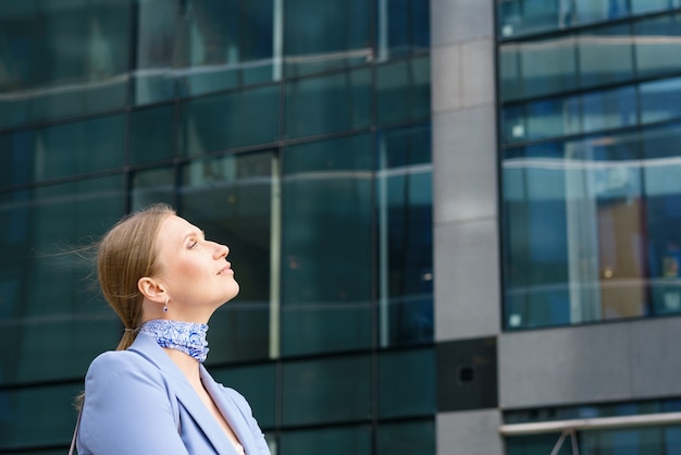 Portrait of a beautiful business of a successful woman in a blue jacket on the background of an office building