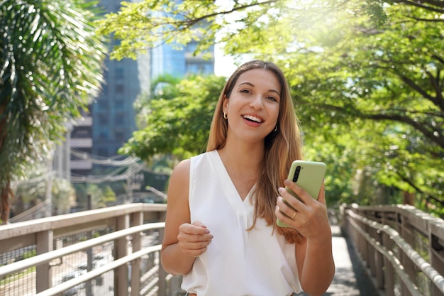 Portrait of beautiful business woman holding smartphone looking at camera outdoor