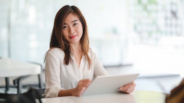 Portrait of beautiful business woman working on her project with tablet and smiling to the camera