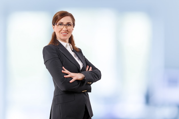 Portrait of a beautiful businesswoman 50 ears old in crossed arms pose in the office.