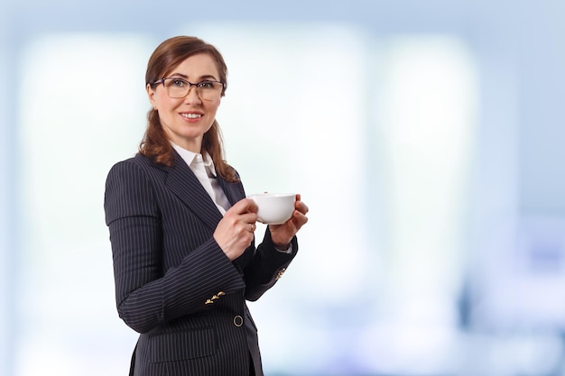 Portrait of a beautiful businesswoman 50 ears old with cup of coffee in the office