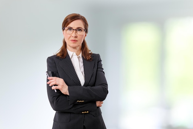 Portrait of a beautiful businesswoman 50 ears old with mobile phone in the office