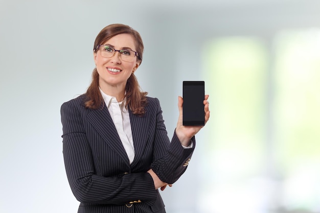 Portrait of a beautiful businesswoman 50 ears old with mobile phone in the office