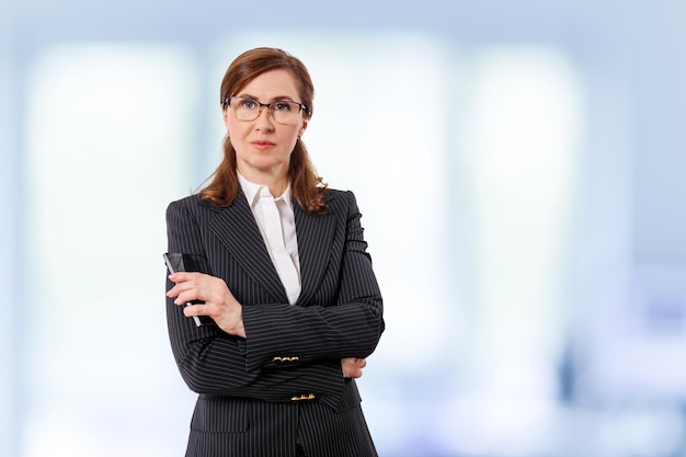 Portrait of a beautiful businesswoman 50 ears old with mobile phone in the office