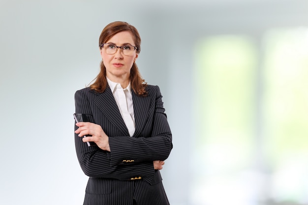 Portrait of a beautiful businesswoman 50 ears old with mobile phone in the office.