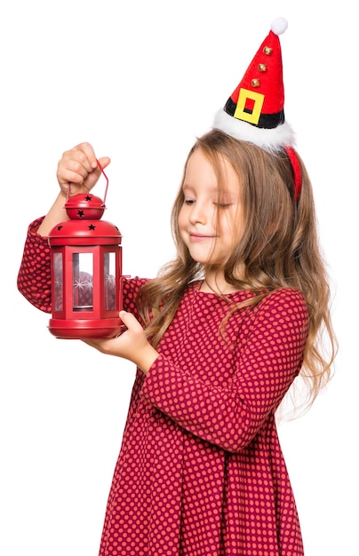 Portrait of a beautiful caucasian little girl wearing small Santa Claus hat isolated on white background Holiday Christmas concept funny child holding red lantern