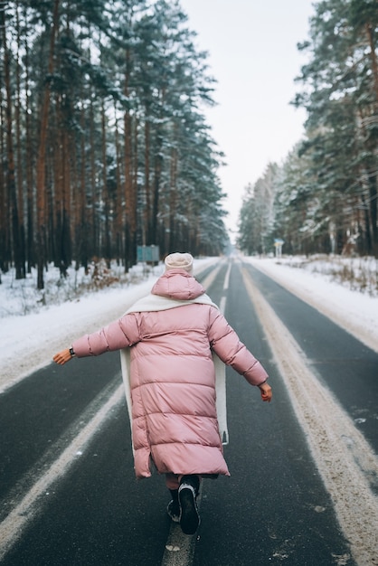 Portrait of a beautiful caucasian woman on a road through snowy forest