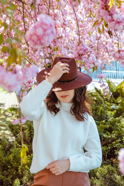 Portrait of beautiful caucasian woman with blooming sakura cherry trees copy space