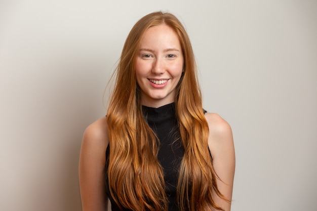 Portrait of beautiful cheerful redhead girl smiling laughing  over white wall