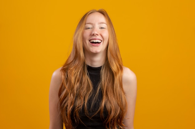 Portrait of beautiful cheerful redhead girl smiling laughing  over yellow wall