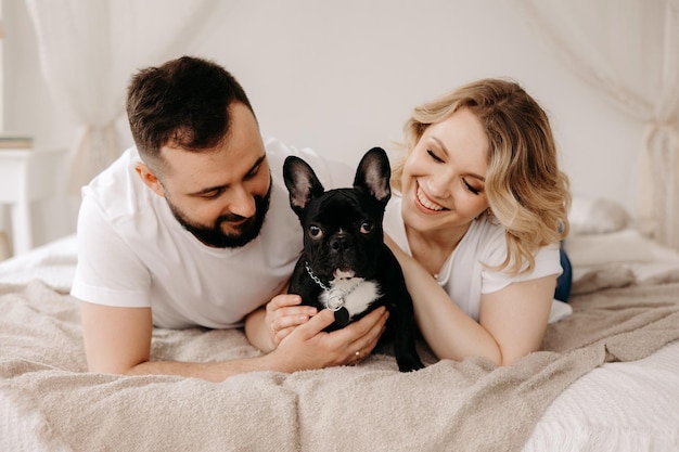 Portrait of beautiful couple and french dog in bed