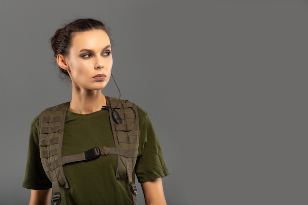 Portrait of beautiful curly brunette with serious expression on the face of female soldier