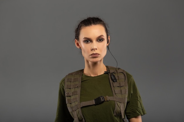 Portrait of beautiful curly brunette with serious expression on the face of female soldier