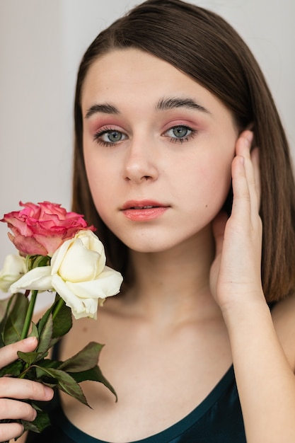 Portrait of beautiful dark-haired woman with flowers. Fashion photo, Pretty little girl with pink rose