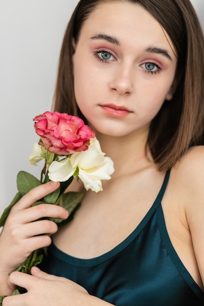 Portrait of beautiful dark-haired woman with flowers. Fashion photo, Pretty little girl with pink rose