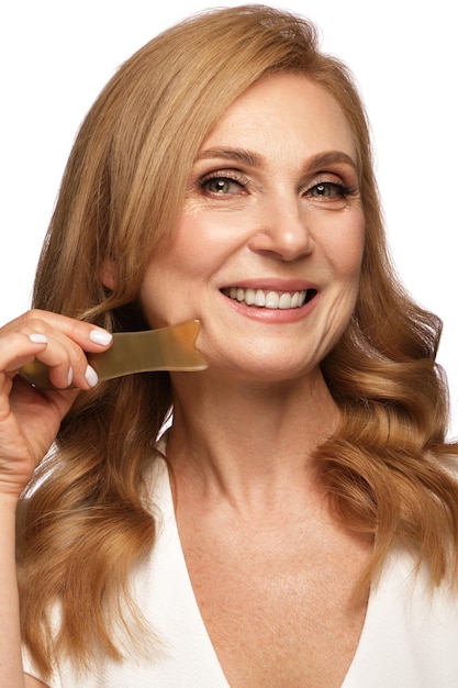 Portrait of a beautiful elderly woman in a white shirt with classic makeup and blond hair