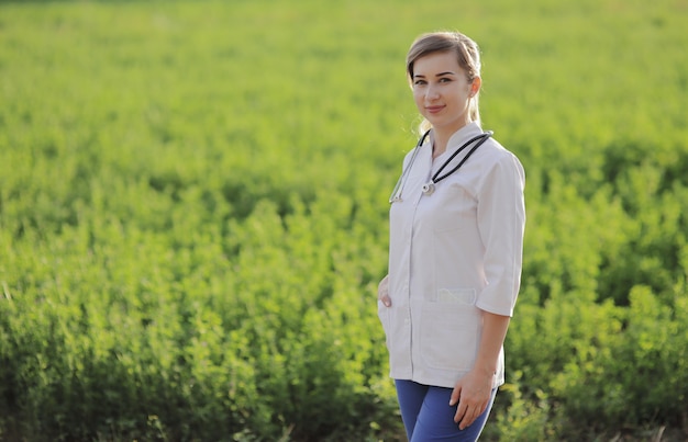 Portrait of a beautiful female doctor or nurse on green grass background