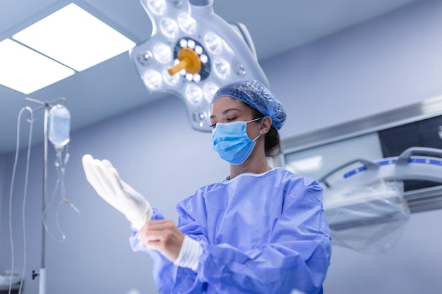 Portrait of beautiful female doctor surgeon putting on medical gloves standing in operation room Surgeon at modern operating room