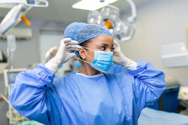 Portrait of beautiful female doctor surgeon putting on medical mask standing in operation room Surgeon at modern operating room