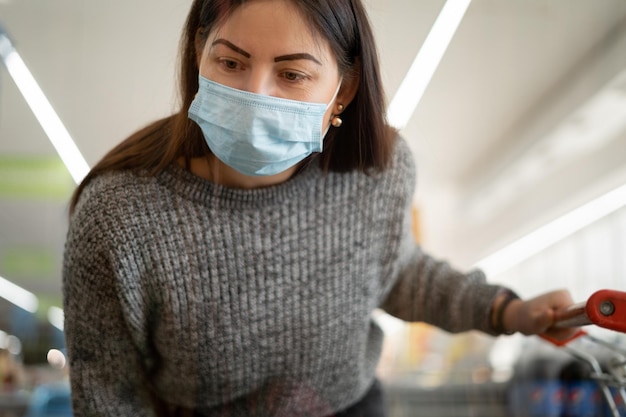 Portrait of a beautiful female shopper in a protective mask in a Caucasian supermarket shopping in the store