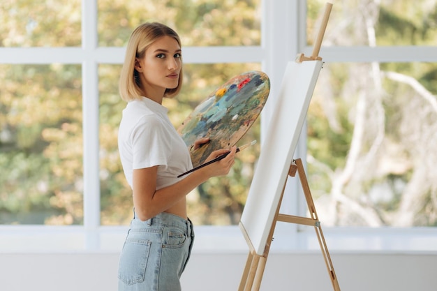 Portrait of beautiful fine artist with palette and paintbrush