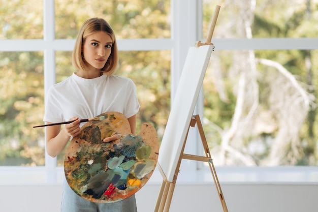 Portrait of beautiful fine artist with palette and paintbrush