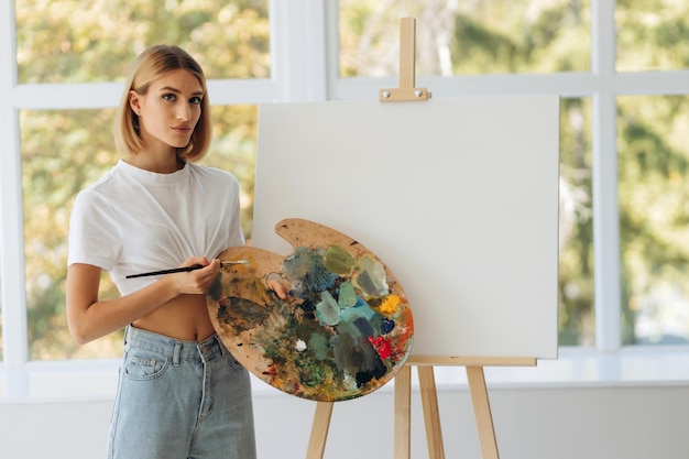 Portrait of beautiful fine artist with palette and paintbrush