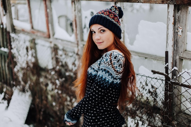 Portrait of beautiful freckled girl with long red hair and cute charming smile wearing gray stylish hat looking and smiling at camera standing against studio wall background Isolated shot horizontal