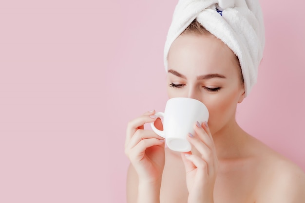 Portrait of beautiful girl in bathrobe with a cup of tea, relaxation concept blonde woman wearing bathrobe and towel on head after shower. Spa woman in bathrobe and turban