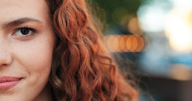 Portrait of beautiful girl of caucasian ethnicity with curly ginger hair standing on the warm spring...