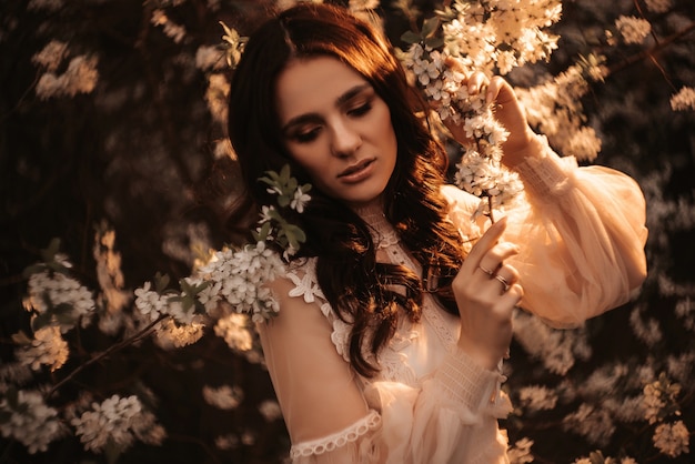 Portrait of a beautiful girl. Flowers background. Against the background of blooming gardens of apple trees .