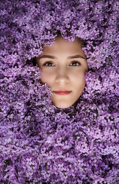 Portrait of a beautiful girl in lilac flowers in the garden spring time