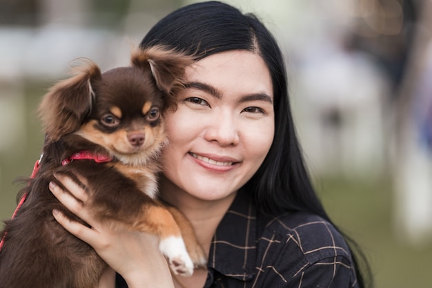 Portrait of a beautiful girl playing with her lovely puppy at outdoor in the public park. Little dog with owner spend a day at the park playing and having fun. Pet love stock photo