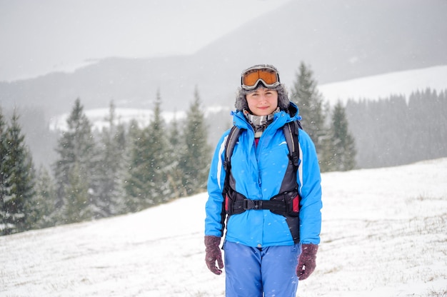 Portrait of beautiful girl on top of snow-covered mountains looking at camera