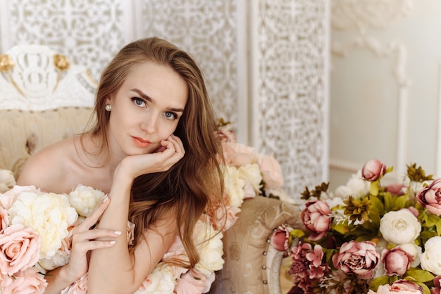 The portrait of beautiful girl with flowers. The amazing girl with flowers in close view. The attractive girl in the pink photo studio