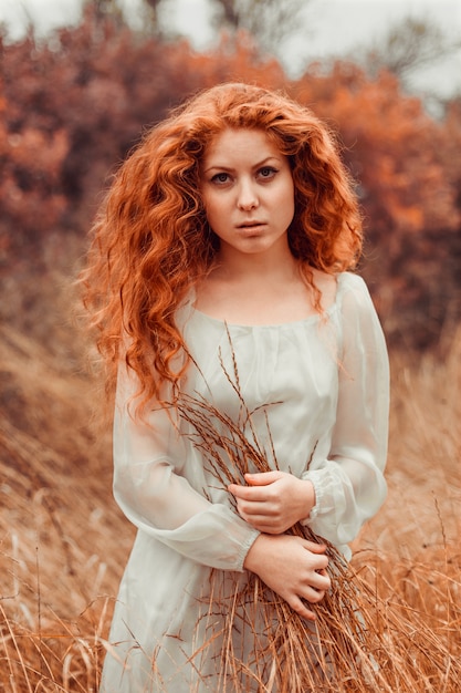 Portrait of a beautiful girl with red hair in the field