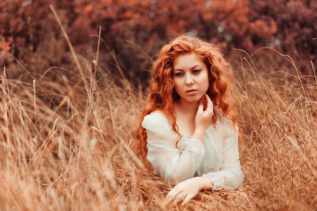 Portrait of a beautiful girl with red hair in the field