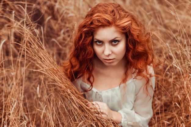 Portrait of a beautiful girl with red hair in the field