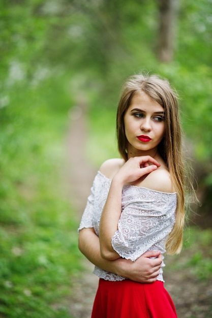 Portrait of beautiful girl with red lips at spring blossom garden, wear on red dress and white blouse.