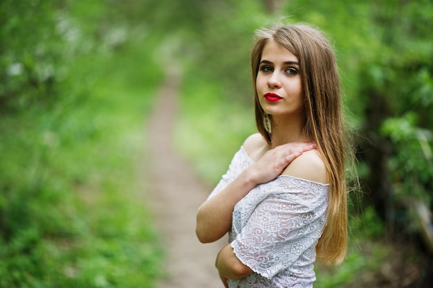 Portrait of beautiful girl with red lips at spring blossom garden, wear on red dress and white blouse.