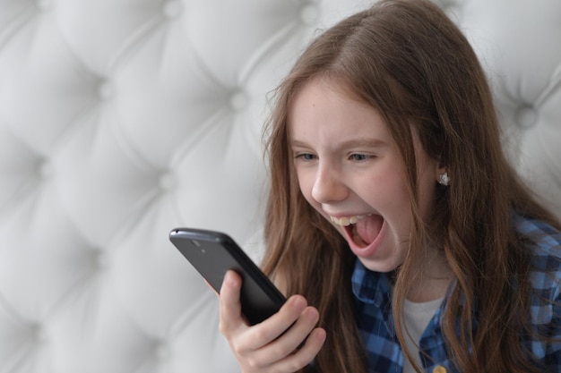 Portrait of Beautiful girl with smartphone at home shouting