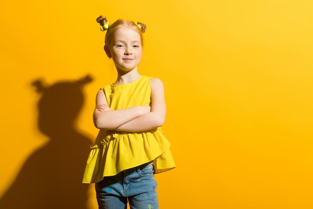 Portrait of a beautiful girl in a yellow blouse and blue jeans.