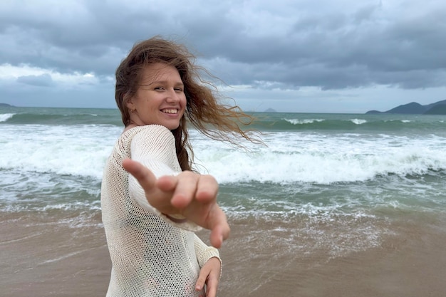 Portrait of beautiful girl young happy positive cheerful joyful woman enjoying vacation on sea ocean walking on summer beach in tropical country smiling having fun laughing in knitted sweater