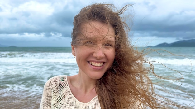 Portrait of beautiful girl young happy positive cheerful joyful woman enjoying vacation on sea ocean walking on summer beach in tropical country smiling having fun laughing in knitted sweater